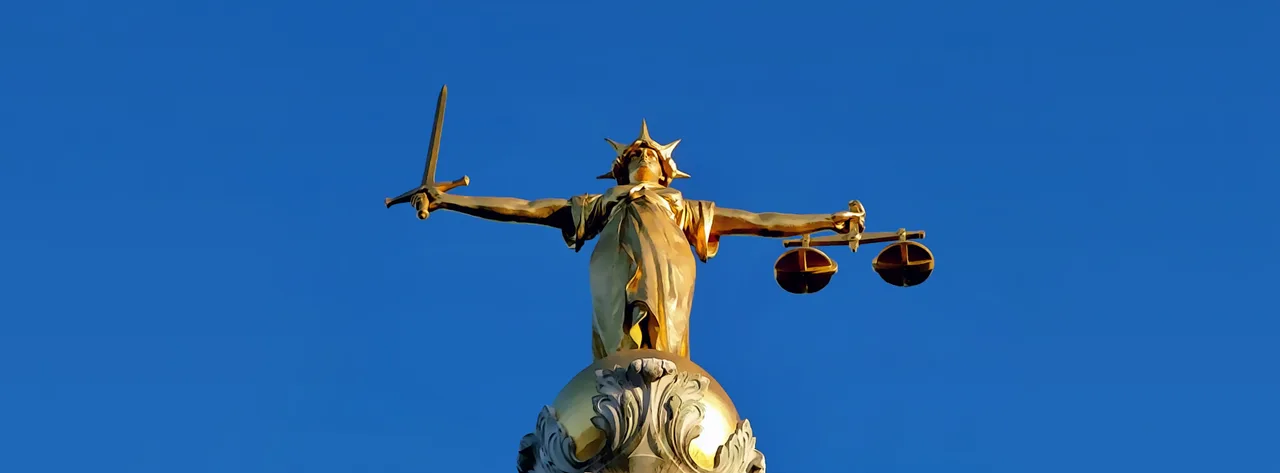 A statue of Lady Justice, a personification of justice, often depicted with scales and a sword, symbolizing fairness and the impartiality of the law, a concept challenged by algorithmic bias.